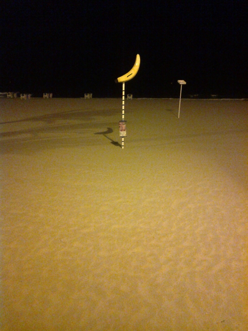 A banana, another beach sign, at night